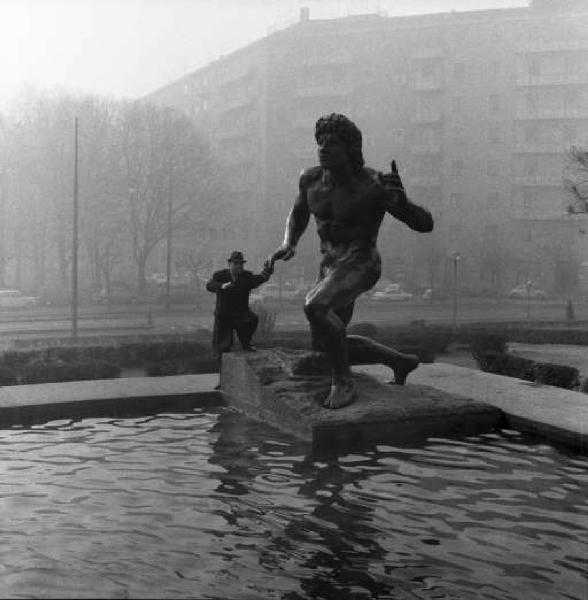 Milano - Un uomo scherza con una statua della fontana monumentale in P -zza Grandi