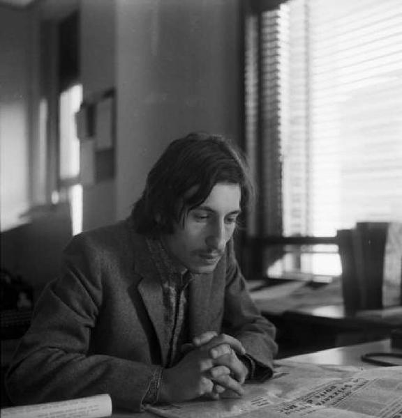 Enzo Nocera [?] seduto alla scrivania legge un articolo di giornale
