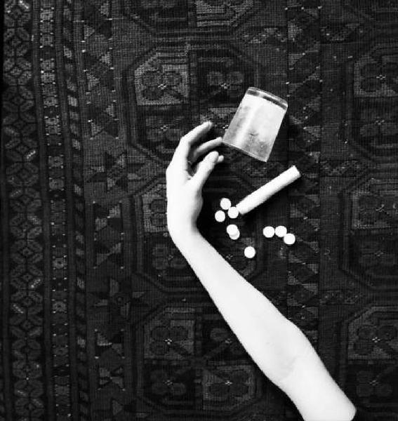 Still - life con braccio disteso su un tappeto, tubetto di pastiglie, pastiglie sparse