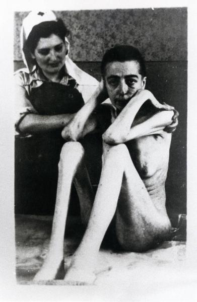Seconda guerra mondiale - Polonia - Campo di concentramento di Auschwitz - Nazismo - Dopo la liberazione - Infermeria, interno - Ritratto femminile: donna prigioniera scheletrica sopravvissuta e liberata - Infermiera della Croce rossa