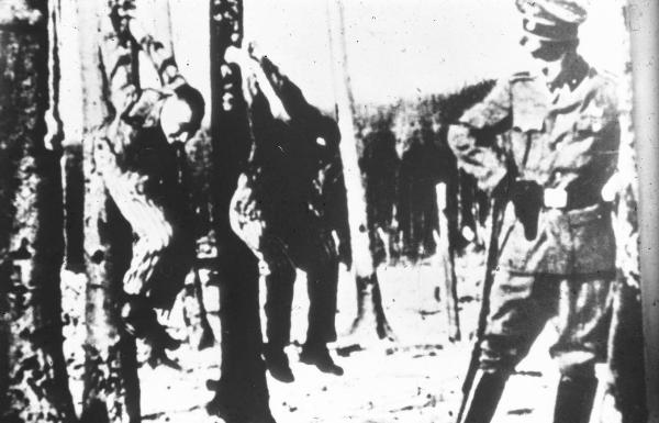 Seconda guerra mondiale - Nazismo - Germania - Campo di concentramento di Buchenwald - Tortura - Prigionieri appesi per le mani a un albero: Karl Schnog (a sinistra), Otto Feuer (a destra), Jack Werber (disteso a terra) - Guardia SS in divisa Sommer