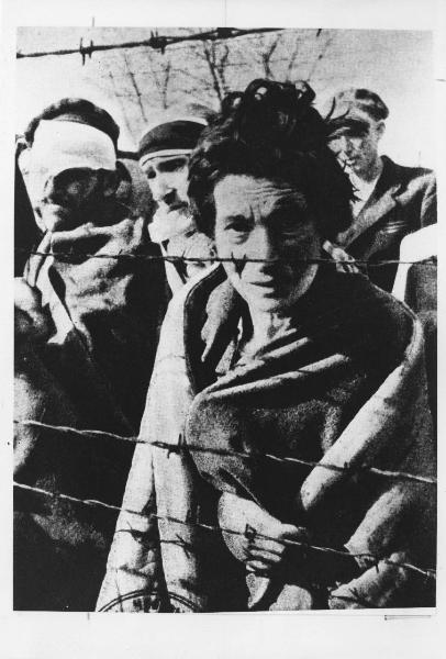 Seconda guerra mondiale - Polonia - Campo di concentramento di Auschwitz - Nazismo - Dopo la liberazione - Ritratto di gruppo: donna e uomini sopravvissuti dietro a reticolato con filo spinato