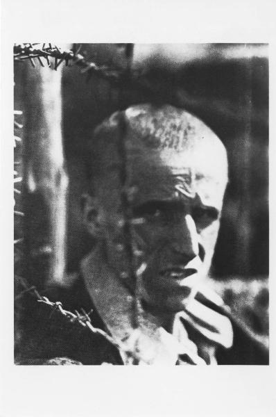 Seconda guerra mondiale - Germania - Campo di concentramento di Bergen Belsen - Nazismo - Liberazione - Ritratto maschile: prigioniero sopravvissuto dietro a reticolato con filo spinato