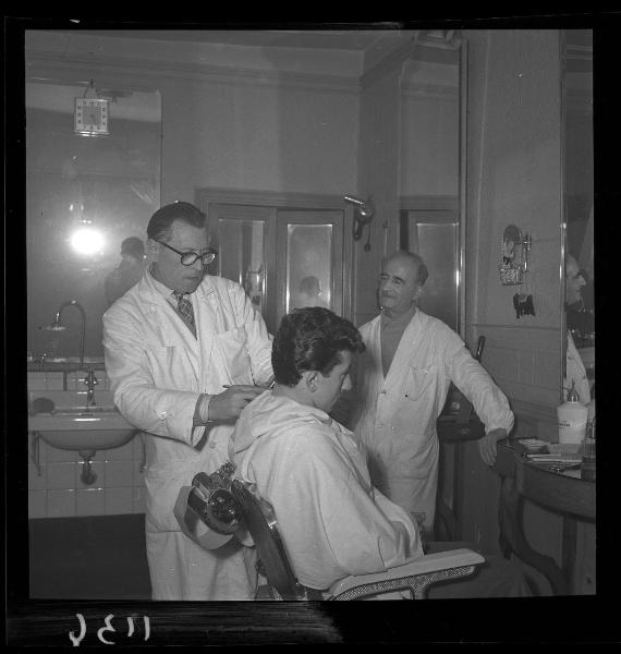 Ritratto di gruppo - Edoardo Maroli durante l'esercizio della sua attività di barbiere con il suo aiutante -  Mantova - Corso V. Emanuele 134 - Interno