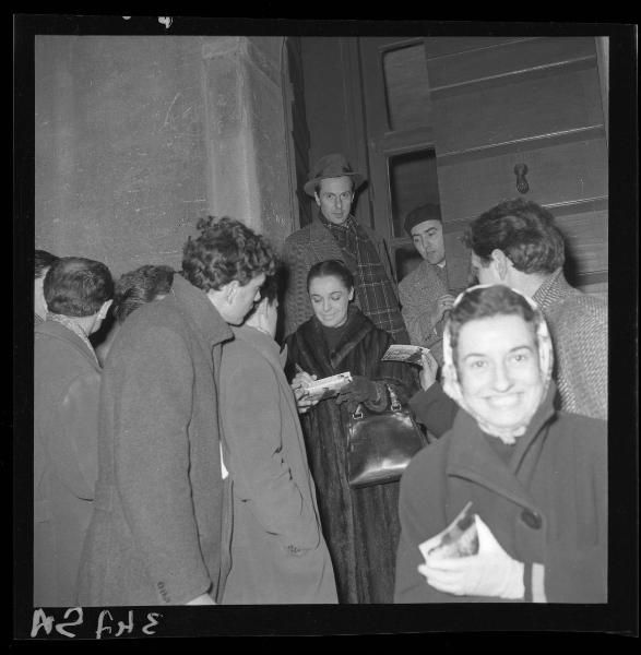 Ritratto di gruppo - L'attrice Anna Proclemer nell'atto di rilasciare autografi a una folla di giovani - Mantova - Ingresso secondario Teatro Sociale - Esterno