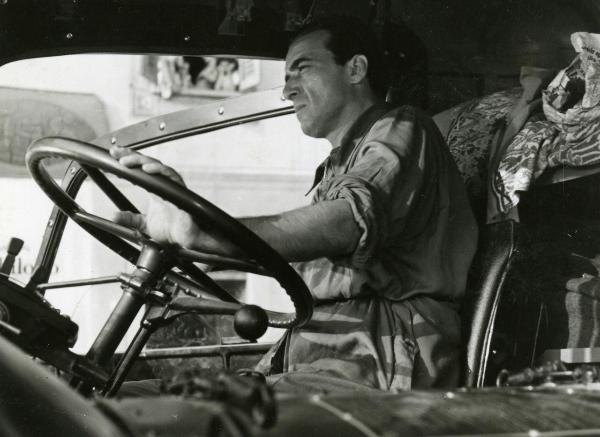 Scena del film "Fari nella nebbia" - Regia Franciolini, Gianni, 1942 - Mezza figura di Fosco Giachetti, in abiti da operaio, mentre rivolge lo sguardo davanti a sé e poggia la mano sinistra sul volante del camion in cui è seduto.