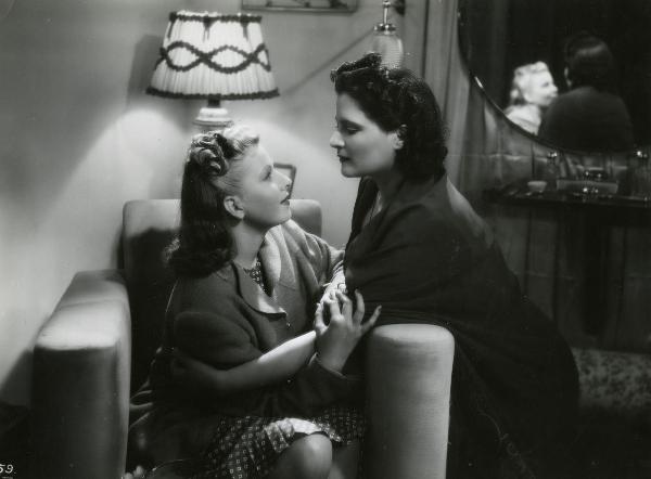 Scena del film "Fascino" - Regia Solito, Giacinto, 1939 - Iva Pacetti, a sinistra seduta su una poltrona, e Silvana Jachino inginocchiata a destra, si stringono in un abbraccio e si guardano intensamente.