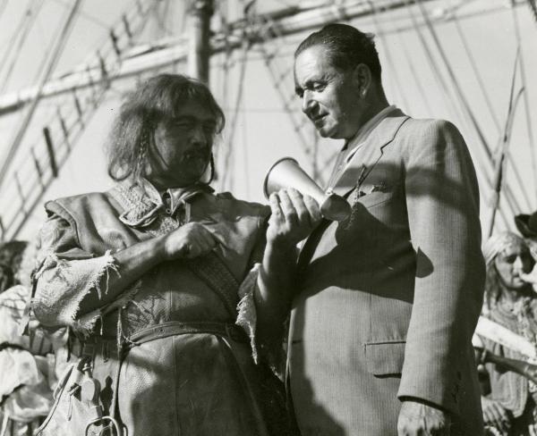 Sul set del film "La figlia del corsaro verde" - Guazzoni, Enrico, 1940 - Camillo Pilotto, a sinistra, parla e tiene in mano un microfono portatile appeso al collo del regista Enrico Guazzoni.
