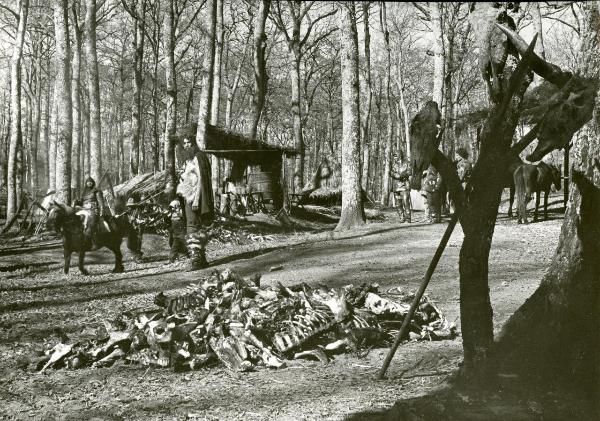 Scena del film "Francesco, giullare di Dio" - Rossellini, Roberto, 1950 - In mezzo al bosco, all'interno di un accampamento, un soldato non identificato e un attore non identificato in veste di pastore guardano verso un mucchio di carcasse animali.
