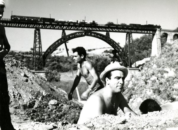 Fotografia sul set di "Un giorno da leoni" - Loy, Nanni, 1961 - Marcello Gatti insieme ad alcuni operatori non identificati mentre lavorano al ponte in miniatura da far saltare.