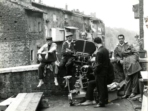 Fotografia sul set di "Un giorno da leoni" - Loy, Nanni, 1961 - Su un muretto, da sinistra a destra: un operatore non identificato, Nanni Loy, un altro operatore non identificato e Marcello Gatti. Davanti, due operatori con la cinepresa.