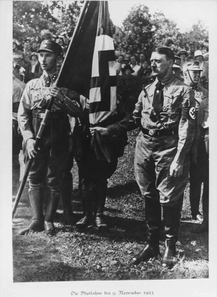 Germania, Monaco - Manifestazione - Ritratto maschile: Adolf Hitler tiene la Blutfahne (bandiera di sangue) del 9 novembre 2023 - Sturmabteilung SA (reparto d'assalto) in divisa - Fascia con croce uncinata / svastica - Nazismo