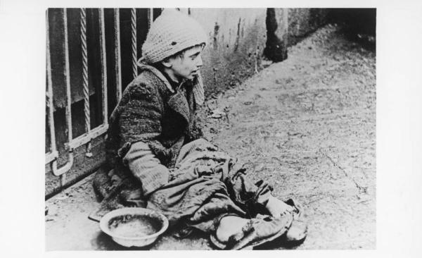 Seconda guerra mondiale - Polonia, Varsavia - Ghetto ebraico - Ritratto infantile: bambino ebreo seduto a terra chiede l'elemosina - Antisemitismo - Nazismo