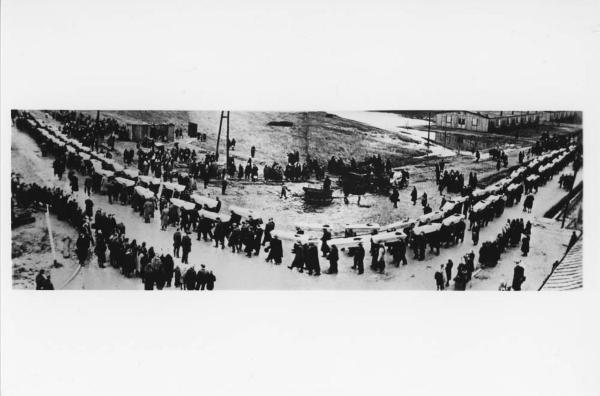 Fotografia dall'alto - Dopoguerra - Polonia - Funerale dei prigionieri trovati morti nel campo di concentramento di Auschwitz - Corteo lungo la strada - Trasporto dei cadaveri nelle bare - Civili