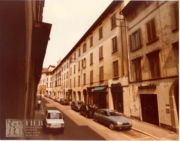 Albergo Commercio - Bergamo - Complesso di Santo Spirito - Esterno: via Torquato Tasso - Automobili parcheggiate - Fiat 126 - Auto Renault - Un uomo e una donna camminano - Negozi - Olivetti