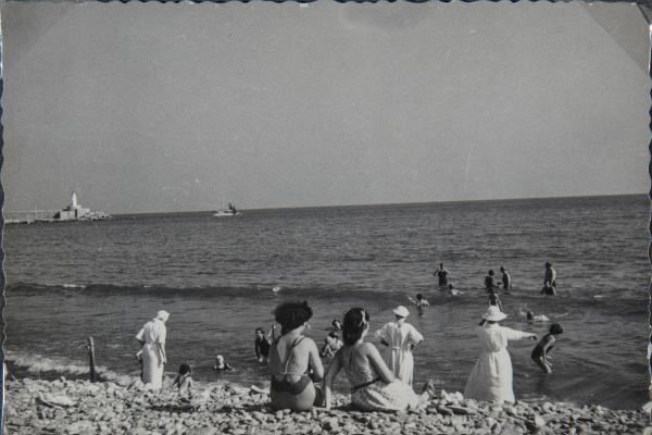 Imperia, Oneglia (?) - Mare - Donne sedute sulla spiaggia e ragazze sorde, allieve del Pio Istituto dei Sordi di via Settembrini in acqua