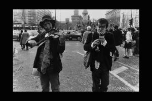 Due ragazzi col volto truccato in Largo Cairoli: uno suona il violino, l'altro il piffero.