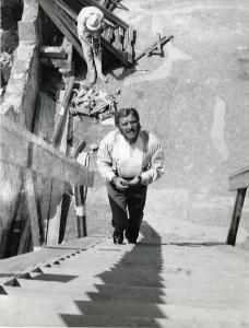 Fotografia sul set di "Il gattopardo" - Visconti, Luchino, 1963 - Figura intera di Burt Lancaster mentre sale degli scalini. Dietro di lui, un operatore non identificato con una macchina fotografica nelle mani.