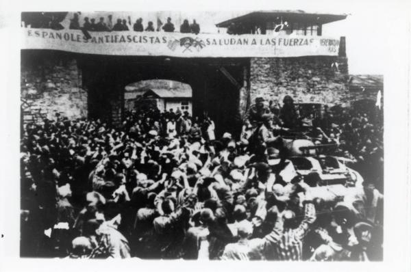 Prigionieri sopravvissuti nel campo di concentramento di Mauthausen danno il benvenuto all’arrivo delle truppe americane. Secondo P. Serge Choumoff, storico e sopravvissuto a Mauthausen, questo evento è stato ricreato il giorno dopo l’effettiva liberazione (5 maggio 1945), su richiesta del generale Eisenhower