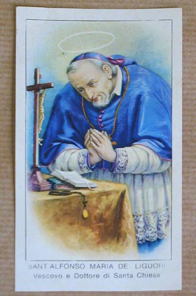S. Alfonzo de' Liguori in abito vescovile mentre prega davanti ad un tavolino col crocefisso, un libro aperto e il rosario
