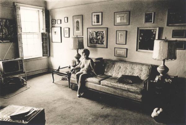 Donna nuda seduta in soggiorno