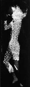 Fotogramma raffigurante sagoma di figura femminile attraverso trama di tessuto decorato
