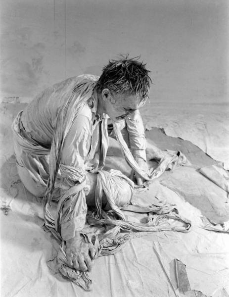 Ana. Performance - Uomo seduto a terra vestito di bende bianche - Pittura sul viso e sul corpo