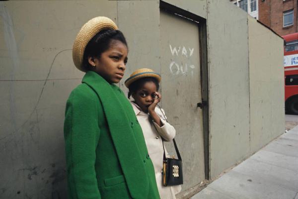 Londra - Esterno - Ritratto di coppia - Due bambine di colore con cappelli di paglia - Cappotti - Borsa - Alle loro spalle una scritta sul muro recita "way out"