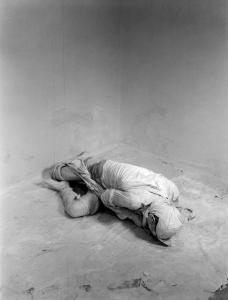 Ana. Performance - Uomo vestito con bendenell'angolo di una stanza vuota
