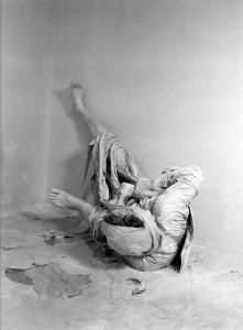 Ana. Performance - Uomo vestito con bende in una stanza vuota - Macchie di pittura bianca sul pavimento