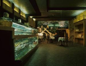 Orvieto dentro l'immagine. Orvieto - Bar, interno - Banco frigo - Tavolini - Un uomo seduto mangia un gelato - Porta con l'insegna "pizze" e freccia