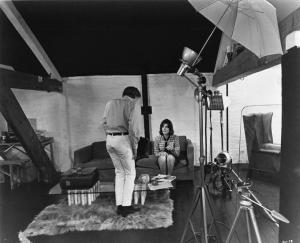 Ritratto. Foto di scena del film Blow-Up. David Hammings di schiena e Vanessa Redgrave seduta su un divano. Luci fotografiche