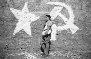 Occupazione delle terre. Ritratto maschile: contadino appoggiato ad un muro - Simboli comunismo dipinti su muro: stella, falce e martello