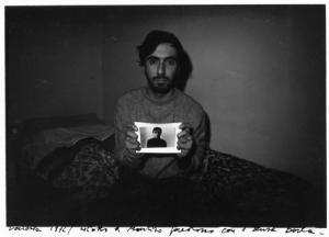 Uomo con in mano una fotografia di se stesso