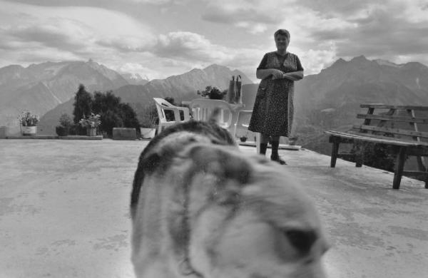 Anziana su un terrazzo fra i monti - cane