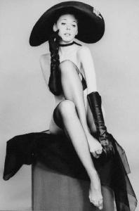 Ritratto femminile: Alicia Brandet, attrice con collant autoreggenti, cappello, guanti e lacrime disegnate sulle guance