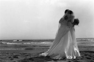 Coppia di sposi abbracciati in riva al mare