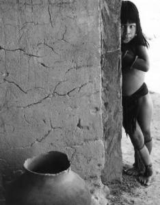 Fanciulla della comunità Indio dei Carajas appoggiata a un muro, davanti a una brocca