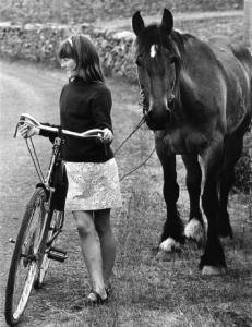 Ragazza con bicicletta passeggia a fianco di un cavallo