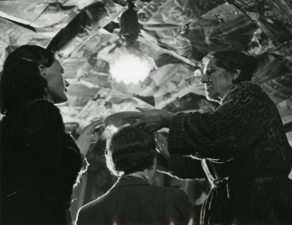 Benevento. La strega - Maria Domenica durante un esorcismo - piatto - bicchiere - donna aiuta a reggere bicchiere in testa a una donna
