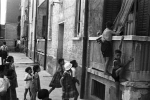 Italia Dopoguerra. Periferia di Milano, le case popolari del quartiere "Baia del Re". Bambini che giocano scavalcando un balcone