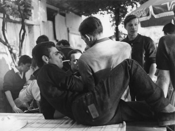 Balera. Italia del Nord - Balera - Cortile interno - Ritratto di gruppo - Ragazzi e ragazzo sdraiato su un tavolo - Sigaretta, fumo