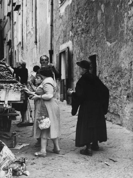 Napoli: Vicoli. Napoli - Vicoli - Fruttivendolo: carretto con la frutta - Venditore ambulante, donne e bambini - Prete con cappello