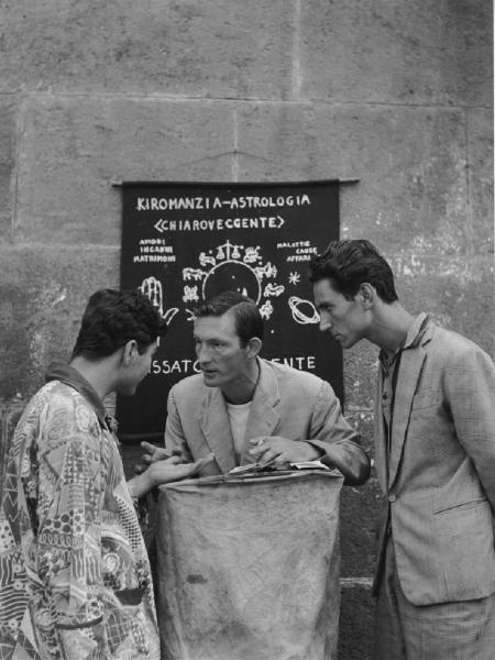 Napoli: Fortuna, fede nella fortuna. Napoli - Vicoli - Ritratto di gruppo - Uomo astrologo al suo banchetto con due ragazzi - Lettura della mano - Oroscopo