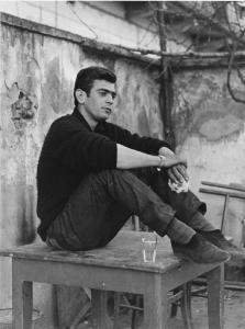 Balera. Italia del Nord - Balera - Cortile interno - Ritratto maschile - Ragazzo seduto su un tavolo - Panino, bicchiere