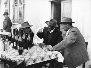 Osteria: Bocce. Italia del Nord - Osteria - Ritratto di gruppo - Anziani con cappello a un tavolo - Bottiglie di vino, bicchieri