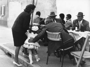 Osteria: Bocce. Italia del Nord - Osteria - Ritratto di famiglia - Anziani, nonni con bambina - Tavola con bottiglie di vino, bicchieri