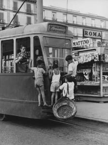 Napoli: Scugnizzi, affetto/ Scene di vita varie. Napoli - Strada con edicola - Bambini viaggiano attaccati sul retro di un tram - Cesto in vimini