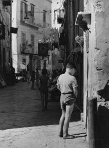 Napoli: Scugnizzi/ Vicoli/ Scene di vita varie. Napoli - Vicoli - Bambino a piedi nudi contro un muro: urina
