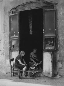 Napoli: Nei Bassi. Napoli - Vicoli - Anziane sedute su sedie sulla porta di casa - Bambina: gioco